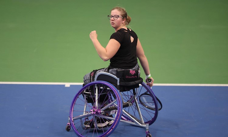 Abbie Breakwell clenching her fist on court while sat in her wheelchair and holding her tennis racket