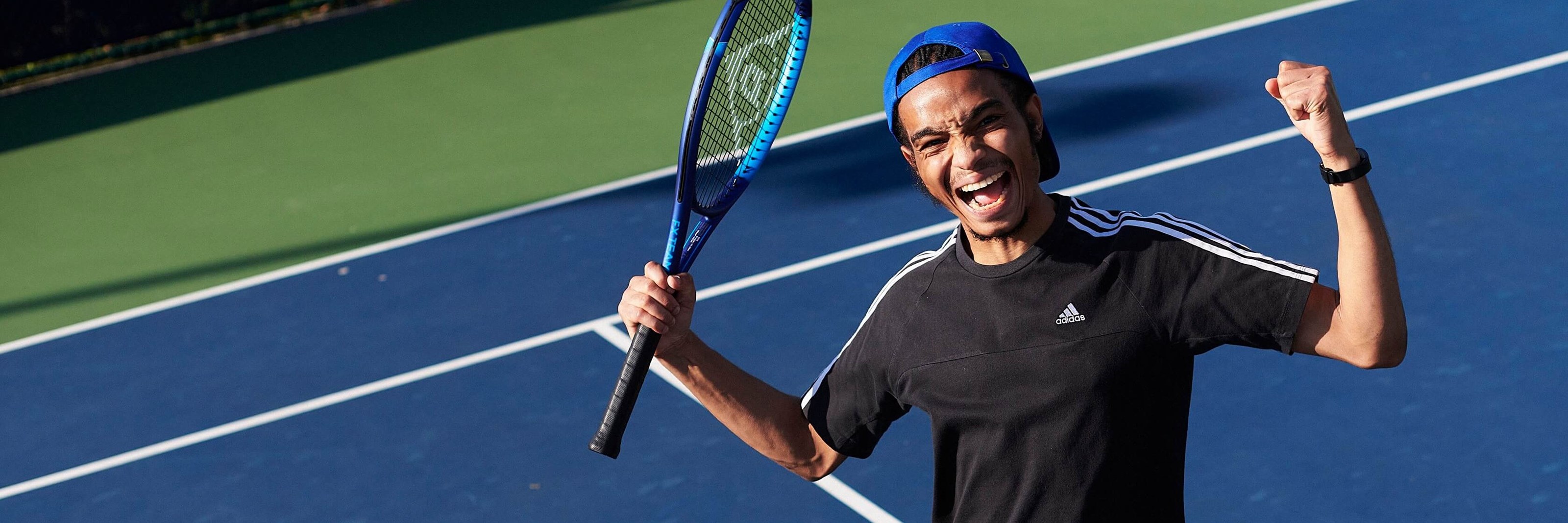 Man jumping up holding tennis racket and laughing