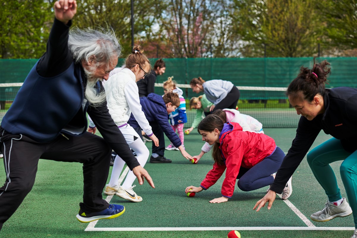 A group of adults and children taking part in an activity at a Barclays Free Park Tennis session