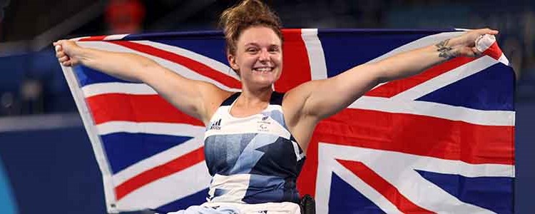 jordanne whiley celebrating holding up large GB flag behind her