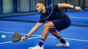 Louie Harris bending down to retrieve a ball with his padel bat on court