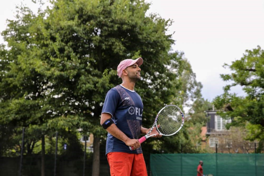 A men holding a tennis racket in a tennis court ready to play 